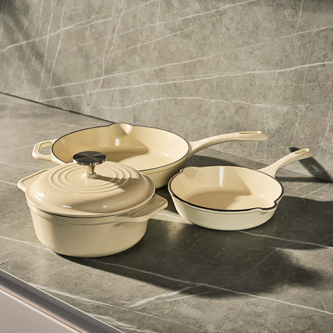 Batería Sable White Victoria con olla tapada y dos sartenes sobre cubierta de cocina