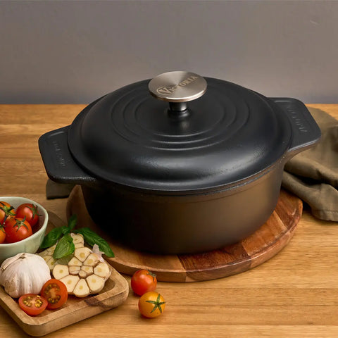 Olla holandesa Victoria de 1.9 L tapada sobre tabla, junto a ajo y jitomates
