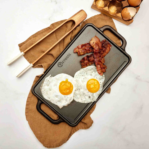 Vista superior de plancha reversible Victoria con dos huevos estrellados y tocino