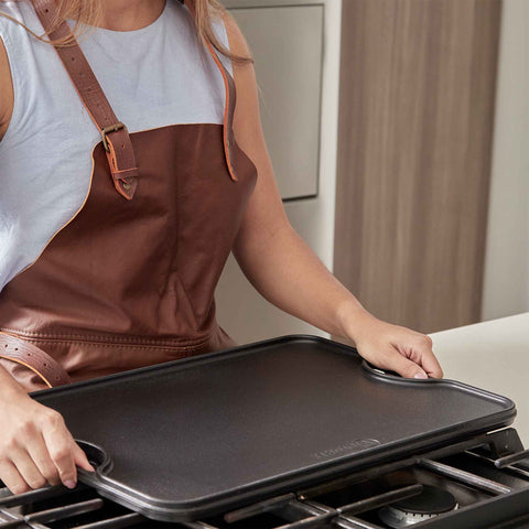 Persona sosteniendo plancha reversible Victoria de 50 × 35 cm con lado liso visible