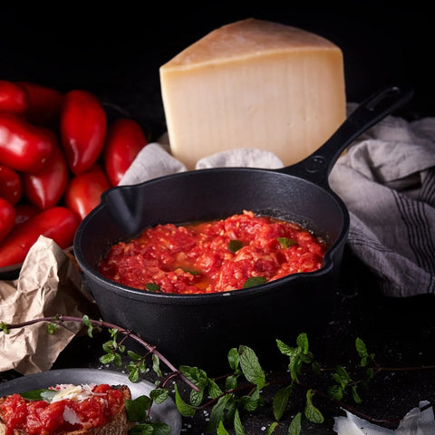 Sartén profundo del kit Victoria con salsa roja, junto a jitomates y un trozo de queso