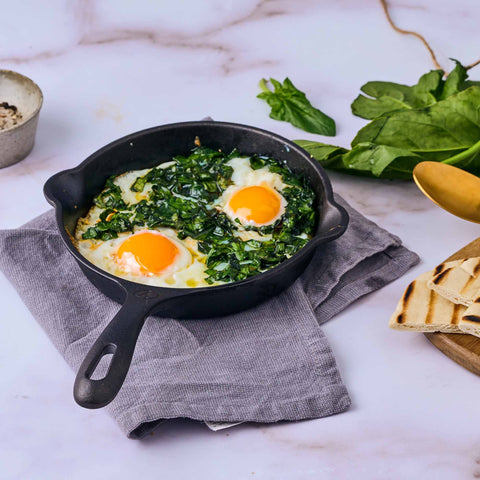 Sartén de 16.5 cm Victoria con dos huevos y espinacas, junto a pan tostado