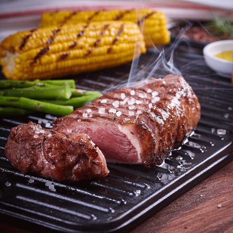 Detalle de plancha reversible Victoria con carne rebanada, sal gruesa y elotes
